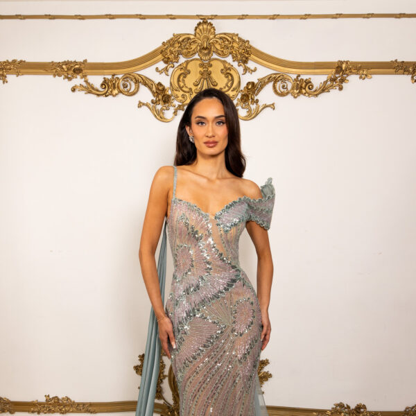 Elegant off-the-shoulder mermaid evening gown in shimmering sage green sequins with intricate floral embroidery, sheer illusion details, asymmetric straps, and flowing chiffon train.