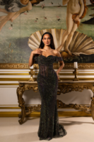 Model wearing a sparkling black off-the-shoulder gown with sheer mesh bodice and floor-length sequined skirt, posed in front of Botticelli's Birth of Venus painting in an ornate gold-framed setting.