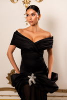 Elegant black off-the-shoulder evening gown with draped bodice, fitted waist, and dramatic peplum detail accented by a sparkling crystal floral brooch.