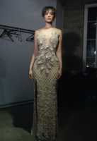 Elegant floor-length evening gown in shimmering nude with intricate silver beadwork, featuring sheer illusion neckline, large floral appliqués on the bodice, fitted silhouette, and high side slit.