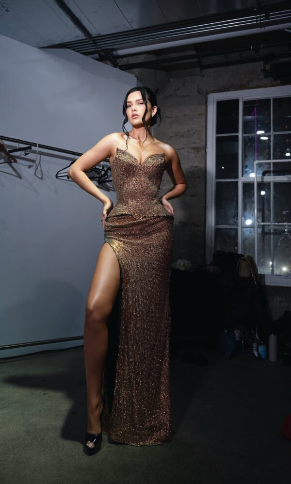 Strapless bronze sequined evening gown with sweetheart neckline, fitted bodice, and high side slit, modeled by a woman posing confidently with hands on hips.